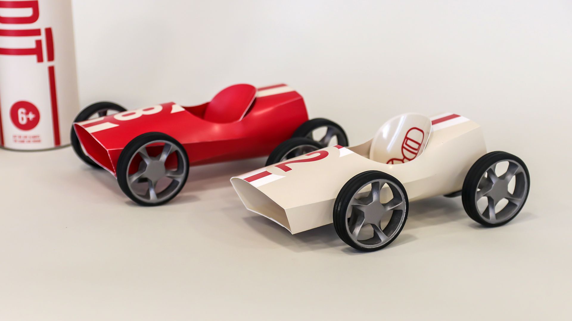 A red Bendit car and a white car with a red stripe, three-quarter view on white.