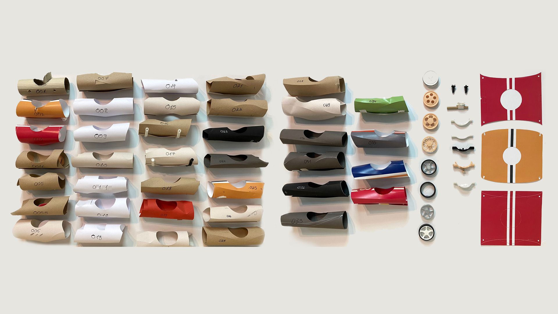 Flat-lay of the Bendit kit — folded cardboard car bodies in many colours with wheels and sticker parts.