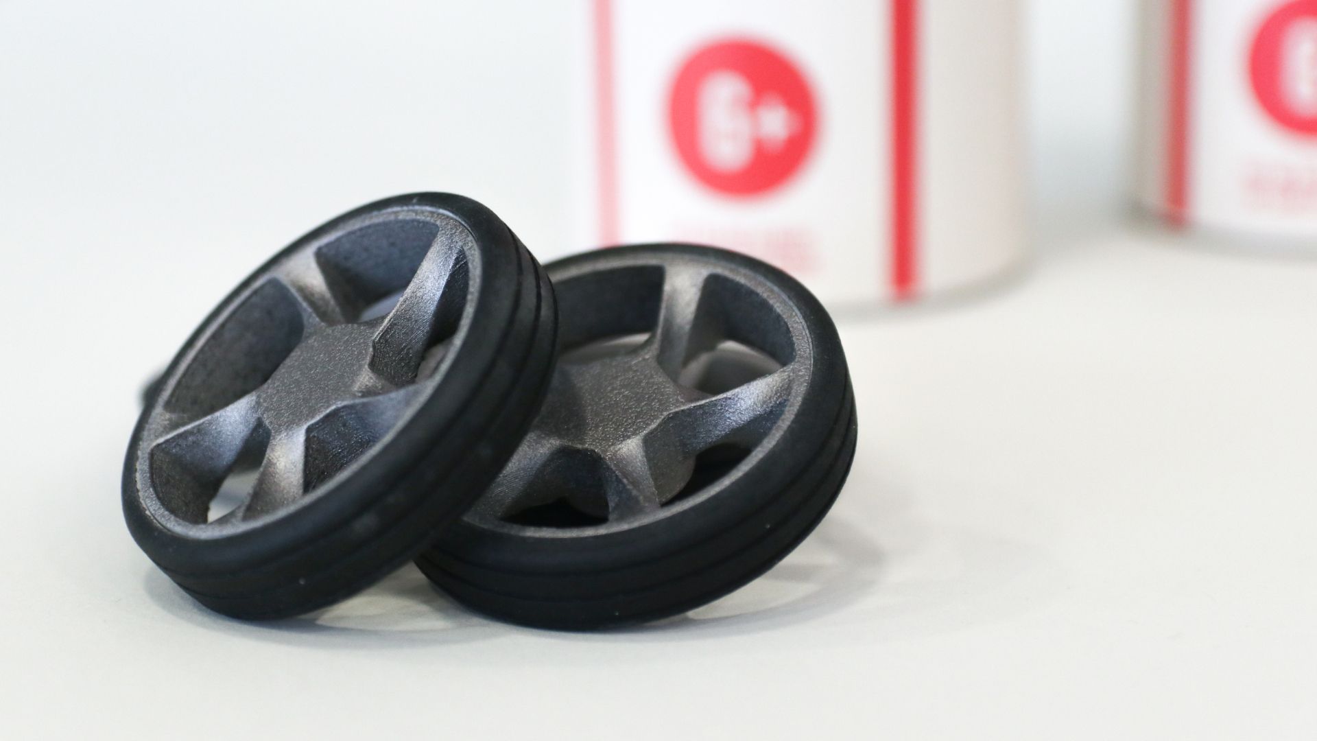 Close-up of two grey five-spoke Bendit toy wheels with the packaging tubes behind.